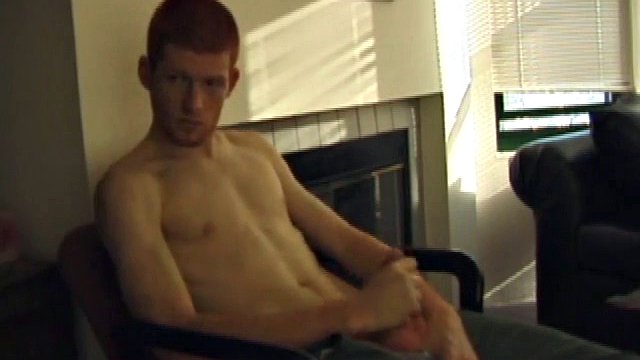 Redhead Tristian relaxes in a chair and gets to work. He's serious about getting down, biting his lip while caressing and watching a porn video. When he stands close to the camera, his red bush is pretty much in your face.